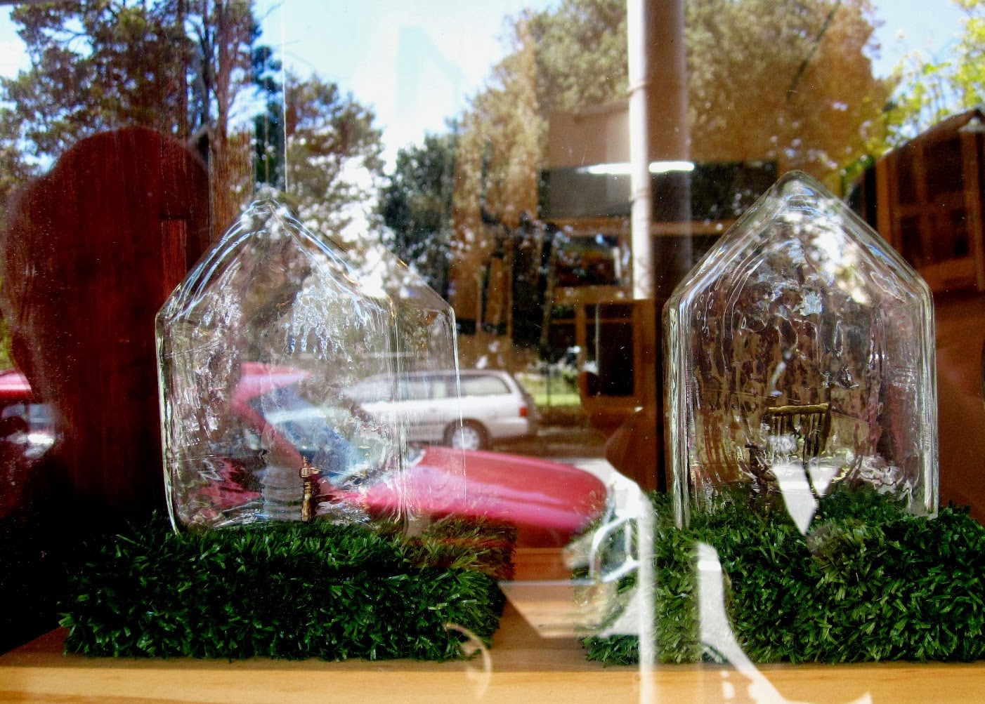 Handmade glass houses with miniature chairs inside, sitting on fake grass