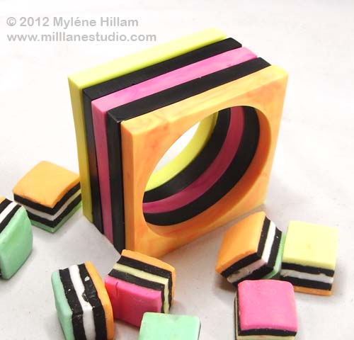 Stack of square black and pastel coloured bangles amongst a group of scattered licorice allsorts.