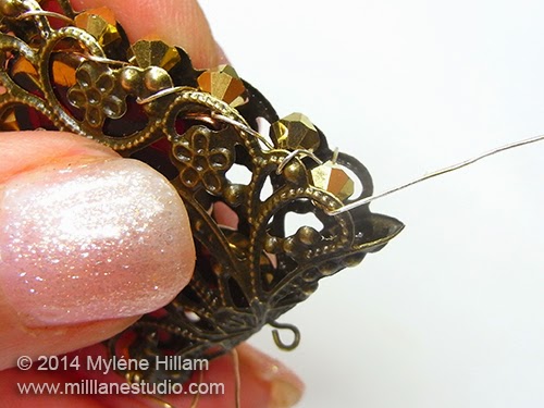 The wire has been wrapped and beaded all the way around the scallops of the filigree.