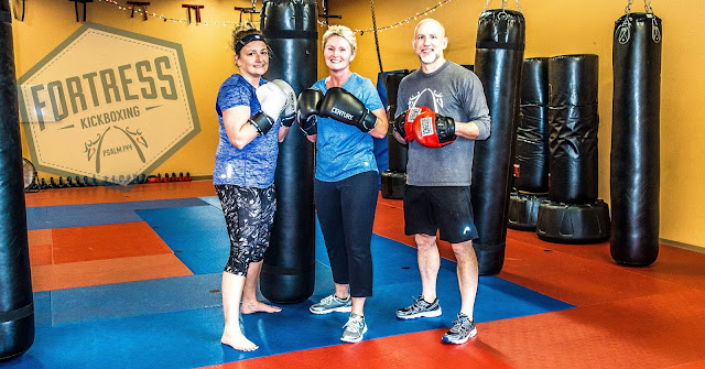 kickboxing students punch bags punch mitts press kettlebells and perform burpees at Fortress Fitness Kickboxing in Morristown TN