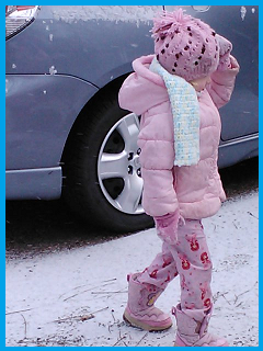 My daughter in a coat over her pink pajamas, boots, gloves, and a hat.  Searching for better snow.