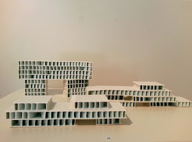 Small porcelain building-shaped works in a gallery.