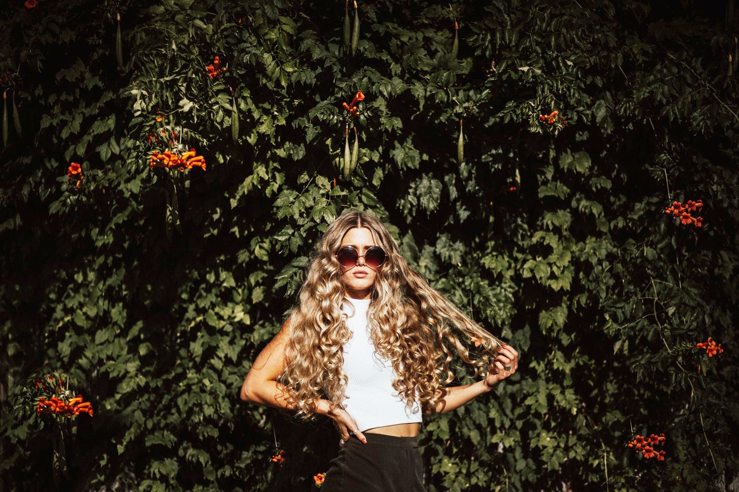 woman with a long, blonde and curly hair oisung in a garden