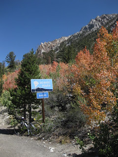 Bicycle, orange aspens, and rocky peaks with sign Begin Scenic Route near Lake Sabrina, Eastern Sierras, California