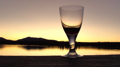 glass of wine with a lake in the back drop