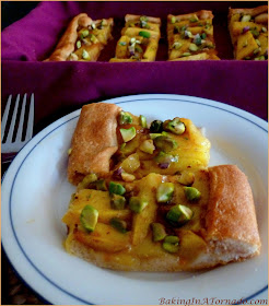 Glazed Mango Tart with Pistachios, a crescent tart topped with ripe mango slices, baked with a glaze, then topped with crunchy topped pistachios. | Recipe developed by www.BakingInATornado.com | #recipe #dessert