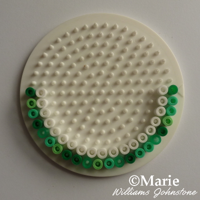 Green and white fused beads around the edge of a circle pegboard hama perler