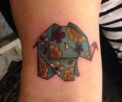 Um origami elefante é acentuado com a mandala de elementos e colorido, com uma paleta de cores, incluindo o azul, amarelo, rosa, roxo e branco.
