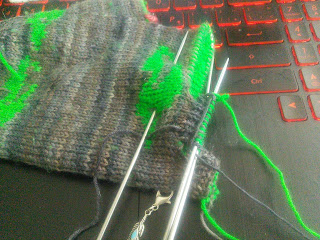 Double-Knit Gloves laying on a computer keyboard.  The top of the glove has been separated into two fingers, with the remaining stitches on a stitch holder. 