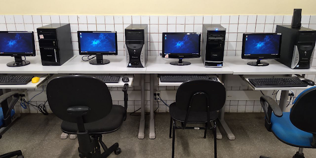 Imagem mostrando o Regata OS instalado em computadores no laboratório de informática.