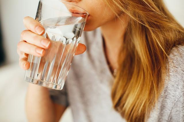Mujer bebiendo agua de un vaso de cristal