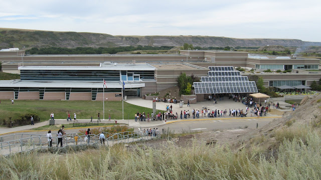The outside of the Royal Tyrrell Museum, seen from a viewpoint on the museum grounds.  You can see the long line of people stretching out from the front door and into the parking lot.