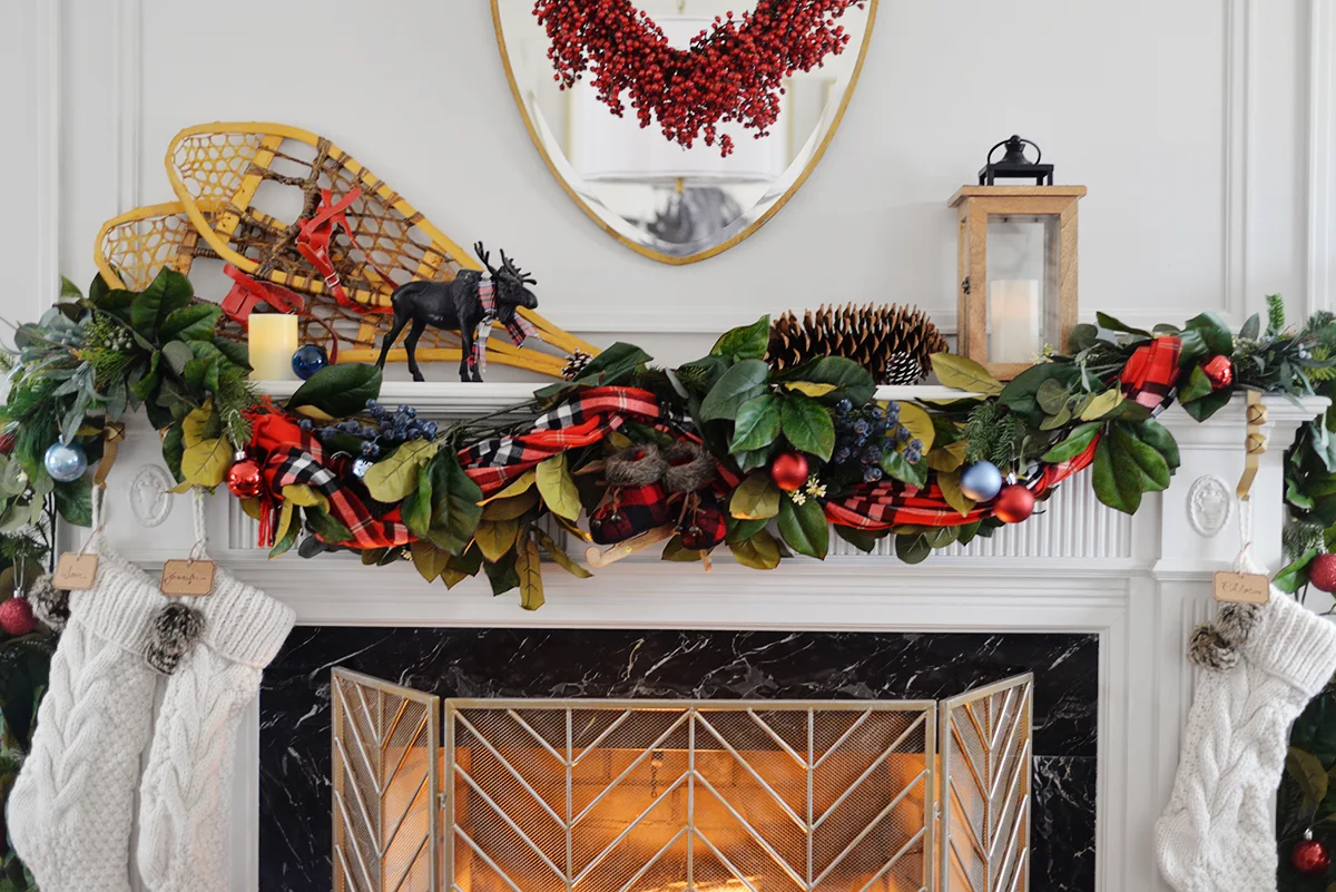 A lush and colourful red and blue Christmas mantel with a plaid scarf, blueberry picks and rustic accents