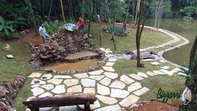 Execução do caminho com pedras em volta do lago com o muro de pedra em volta do lago, sendo caminho com pedra cacão de São Tomé com junta de grama.