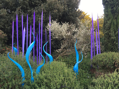 bright blue and purple glass 'reeds' and 'leaves' in a garden bed