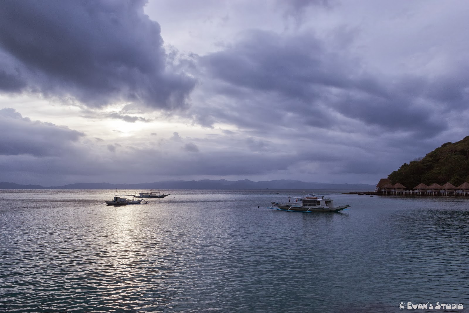 Three ships sit at the outskirts of Apulit Island Resort during dusk.