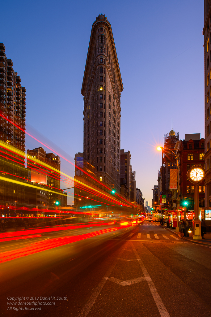 a photo of the flatiron building at night with traffic trails new york