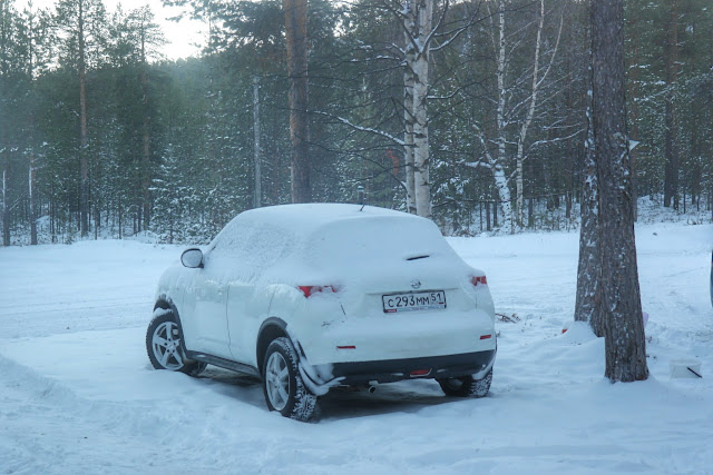 Carro coberto de neve em em Ivalo, Finlândia Carro coberto de neve entre árvores em em Ivalo, Finlândia