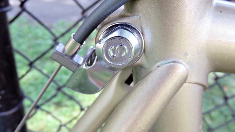 Schwinn bicycle seat clamp against chain fence.