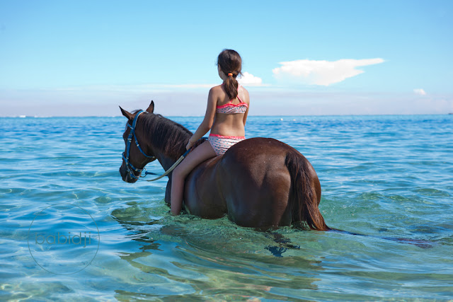 Enfant à cheval dans l'océan indien au Morne à l'île maurice jeune cavalière à cheval dans la mer sur la plage du Morne à l'Île Maurice