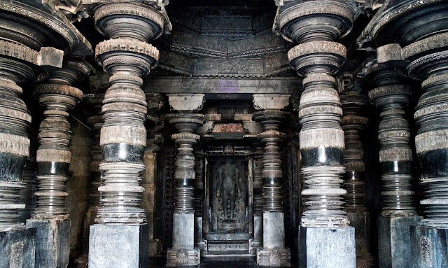 10 of the 12 elegantly carved pillars of the navaranga, Parshvanatha statue at the center, and the ceiling sculptures partially visible through the door. 10 of the 12 elegantly carved pillars of the navaranga, Parshvanatha statue at the center, and the ceiling sculptures partially visible through the door.