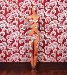model painted to blend in with red and whie floral wallpaper