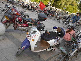 electric scooter with an American flag and "go with me" design with a Chinese flag flying on it in Mudanjiang, China