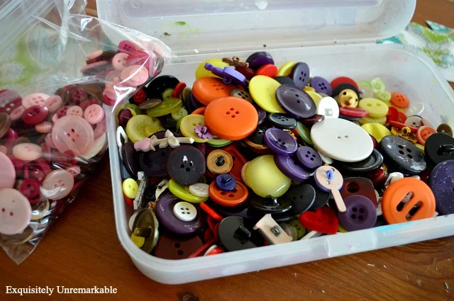 Plastic box full of multicolored craft buttons
