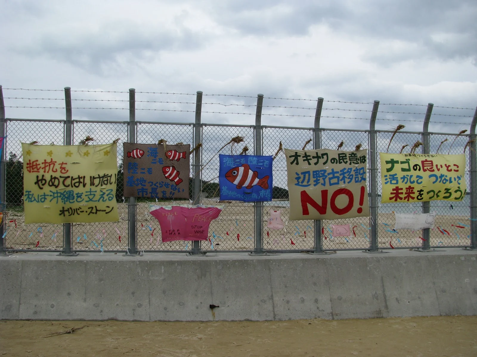 沖縄県名護市辺野古のアメリカの軍事基地：キャンプシュワブの地元住民の基地反対の看板が幾つもかけられた金網