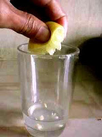 Squeezing a piece of lemon between the fingers to extract its juice.