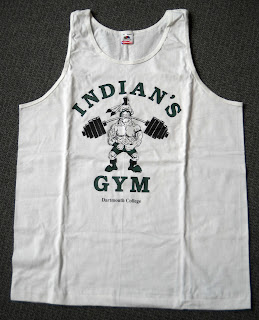 A sleeveless white shirt showing the "Dartmouth Indian" lifting weights with his teeth.