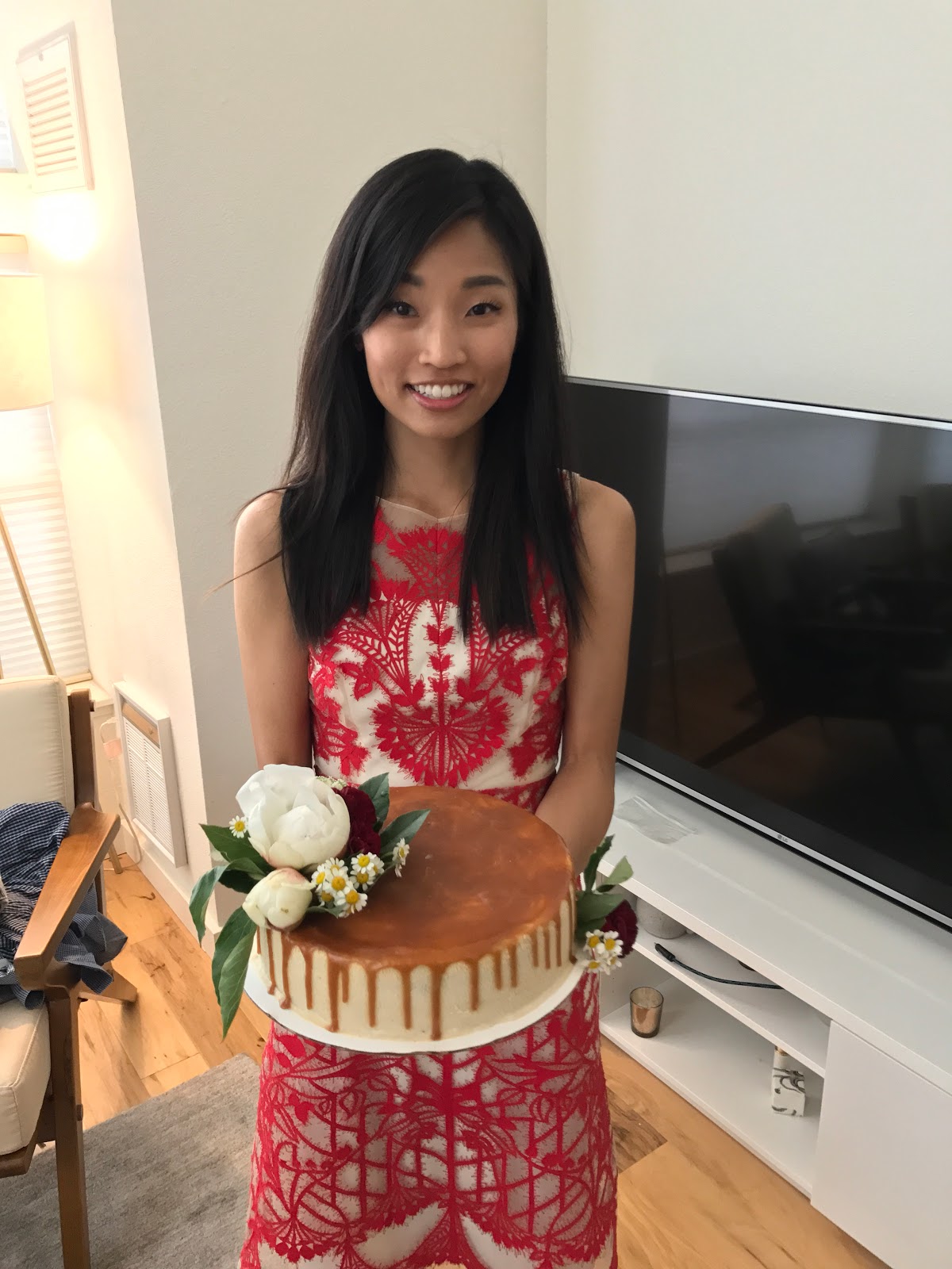Jen Lee of The Jen Project holding her homemade earl grey and salted caramel cheesecake with white peonies, red carnations, chamomile, and green mist