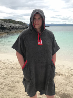 man on beach in hooded towel with sea in background 