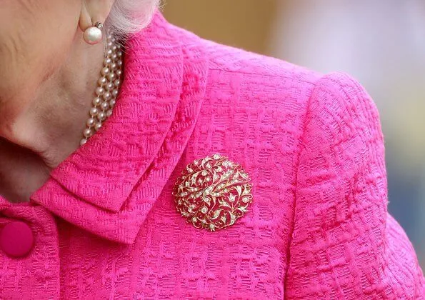 Queen Elizabeth wore a floral satin dress, pink coat and pink hat, pearl necklace, pearl earrings and diamond brooch