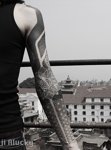 Encantamento tribal tatuagem manga. O projeto começa com cores fortes e transições em uma imagem de uma flor e mais se decompõe em imagens de flores pequenas, preenchendo a totalidade do antebraço.