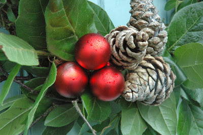 Red baubles, pine cones and birch twigs on a fresh viburnum leaf Christmas wreath.