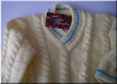 Blusa infantil branca com detalhes em azul na gola e nos punhos, feita em tricô manual com lã acrílica