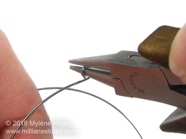 Turning a loop on the memory wire with round nose pliers.