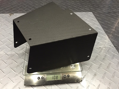 Bespoke matte lacquered carbon Caterham pedal box cover on the scales weighs just 108g