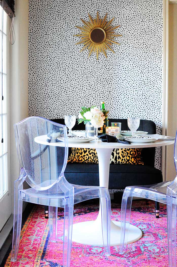 $100 Dining Space Makeover in an Apartment: pink rug, temporary wallpaper, sunburst mirror, IKEA docksta table and ghost chairs.