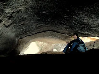 Hiker rests amidst the dark caves at the summit of Nijagal betta trek