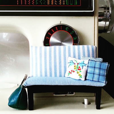 Modern miniature padded bench in blue and white, with toning cushions, displayed on a full-sized sewing machine.