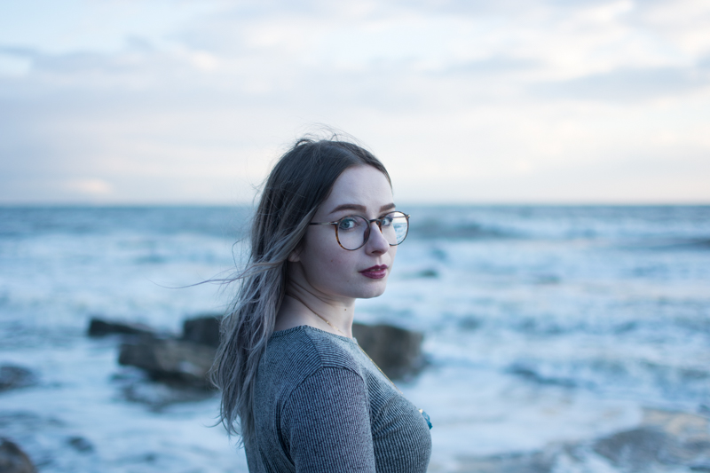 portrait of a girl on the beach long sleeve crop top black milk ancient maps bodycon dress big hipster glasses crystal necklace
