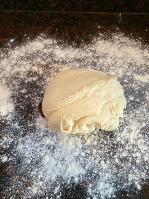 Flour on the counter with a ball of bread dough on it. 