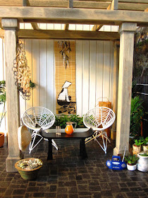 One-twelfth scale modern miniature patio scene with wire chairs, a gazebo and many plants.