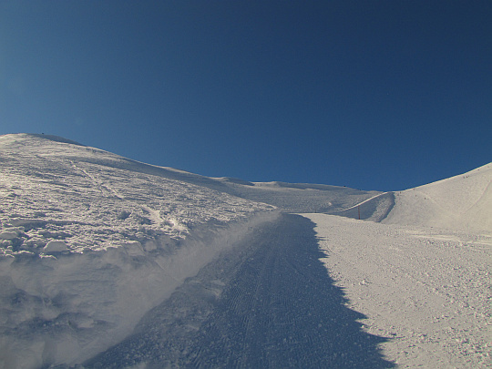 Wyratrakowany szlak wznoszący się trawersem po stoku Beskidu wzdłuż trasy narciarskiej.