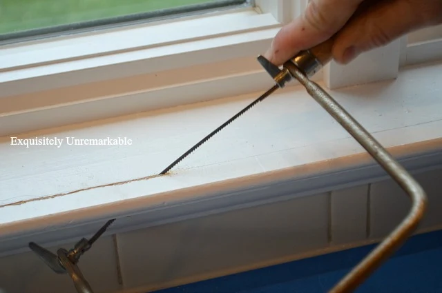 Using A Hacksaw To Cut Back A Windowsill