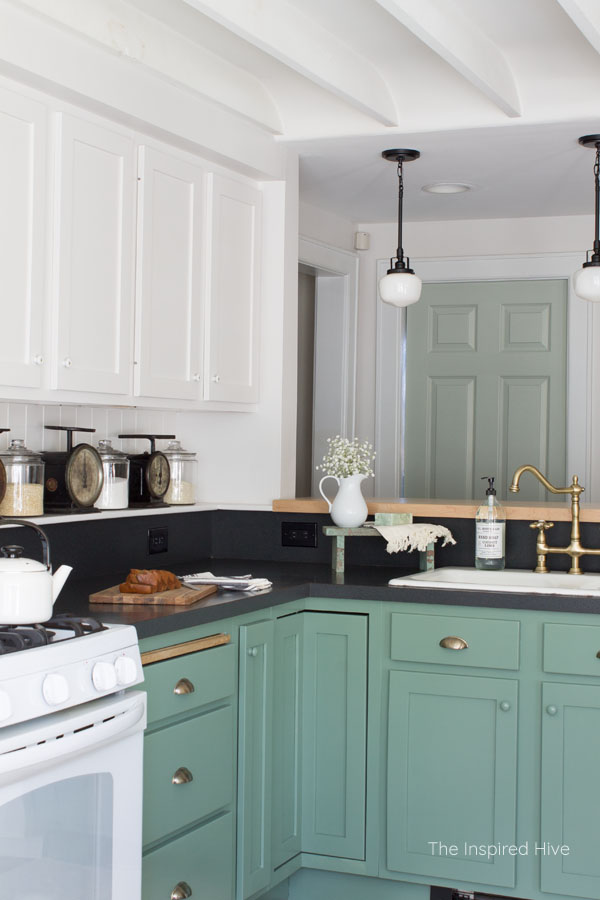 A cozy modern farmhouse kitchen with 1920s vintage charm. Exposed ceiling, schoolhouse lights, brass hardware, and porcelain knobs give this kitchen antique style.