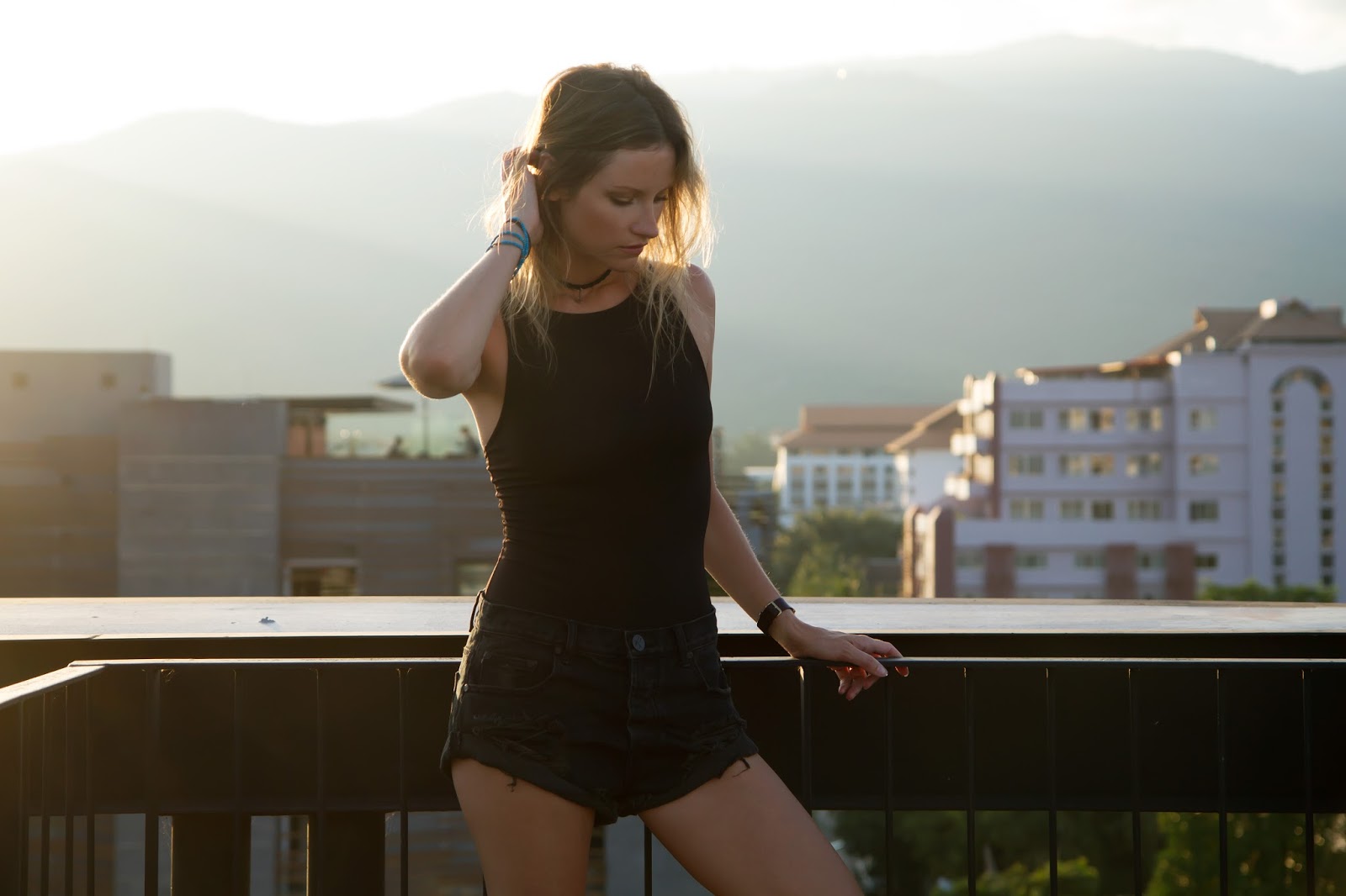 Fashion/Travel blogger and digital nomad, Alison Hutchinson of Styling My Life, is wearing a black Topshop bodysuit and black One Teaspoon Bandits with NIke Trainers on a rooftop overlooking Chinag Mai