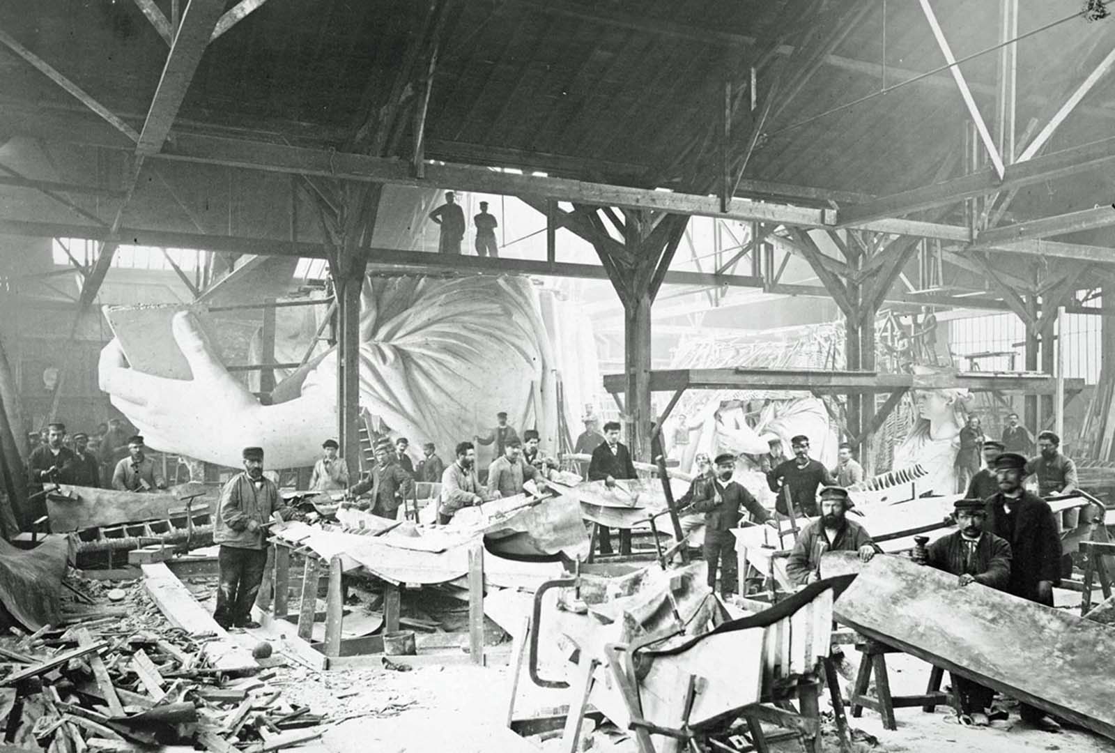 Men in a workshop hammer sheets of copper for the construction of the Statue of Liberty in 1883.